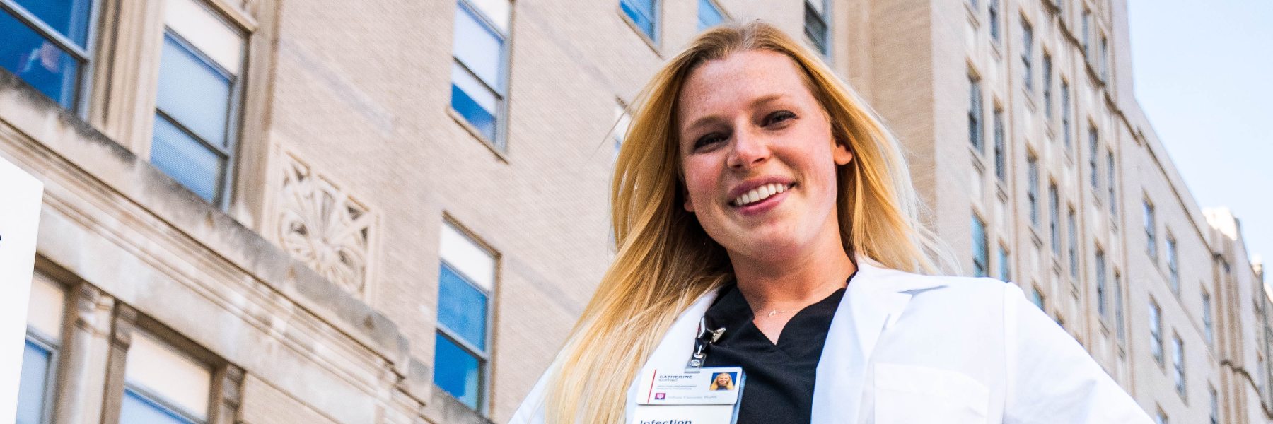 woman in white coat in front of medical building